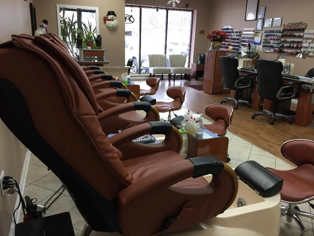 Massage pedicure chairs in a row, with manicure tables and a wall of polish at the back