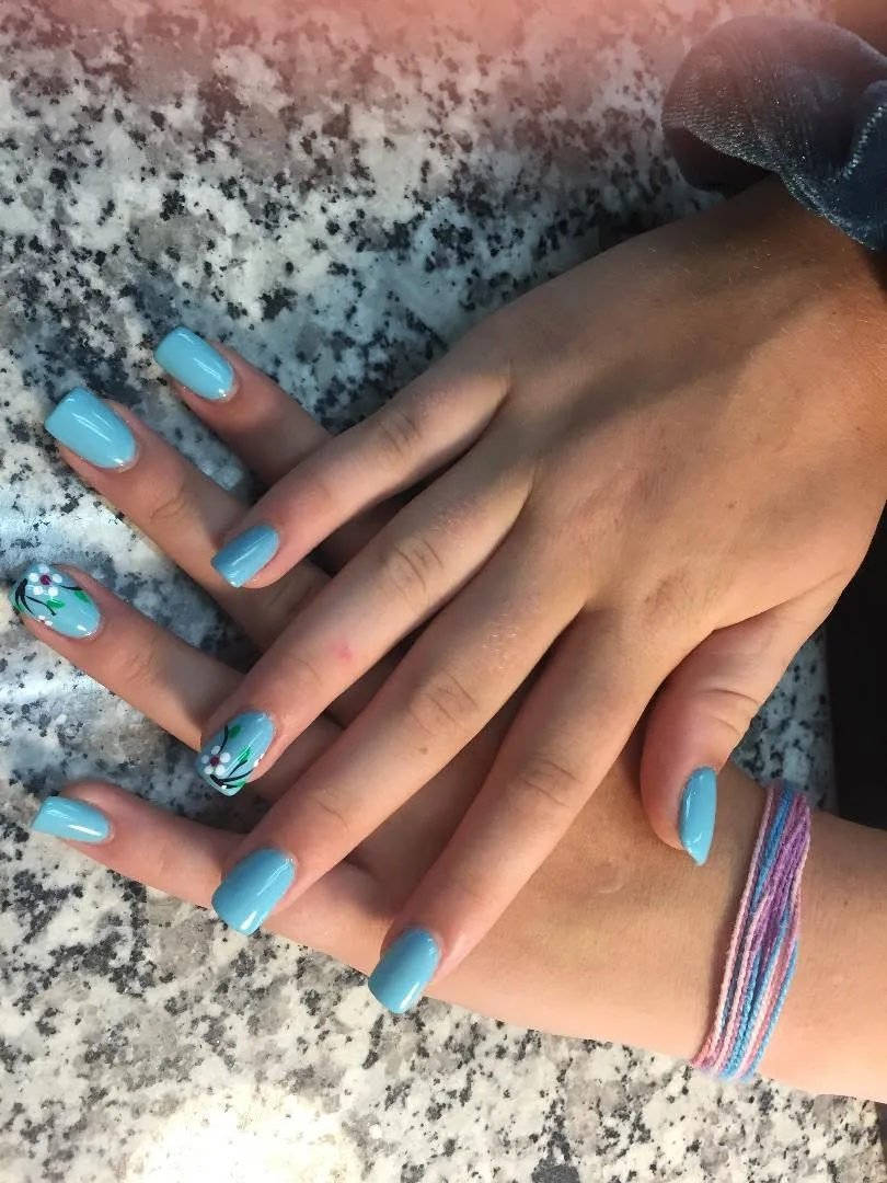 Light blue nails, two of them painted with white flowers on black branches
